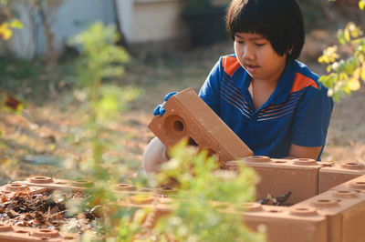 Boy arranging bricks outdoors