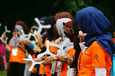 Group of woman holding boomerangs while standing outdoors
