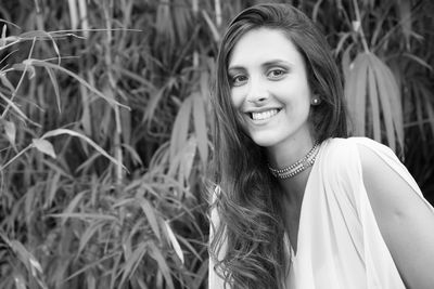 Portrait of smiling young woman standing against trees