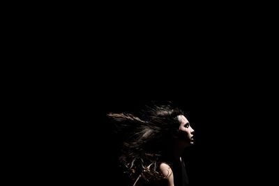 Woman with tousled hair against black background