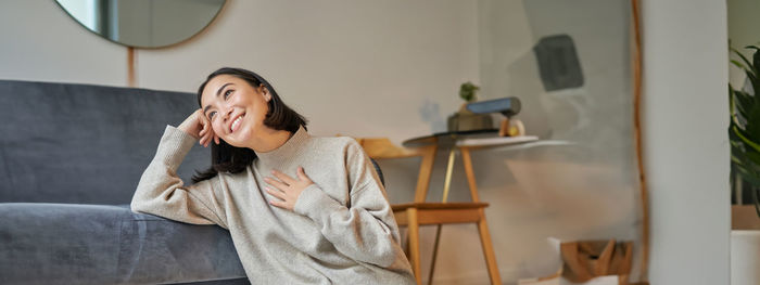 Portrait of young woman standing against wall