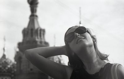 Young woman with hand in hair against sky