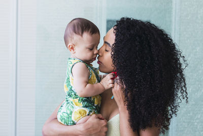 Woman with curly hair embracing cute toddler son at home