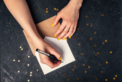 A woman writes plans for 2022 on black background top view