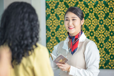 At the airport check-in counter, a passenger hands over his documents to the manager via a counter 