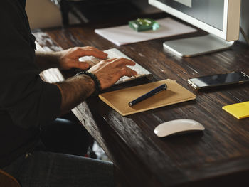 Detail of man hands working at home desk with computer via internet typing on computer