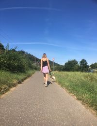 Full length of woman with dog on road against sky