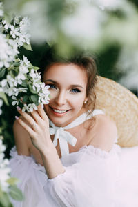 Beautiful bride in a wedding dress walks in a blooming apple-tree park in spring