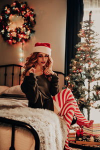 Portrait of woman sitting on bed at home, christmas themed.