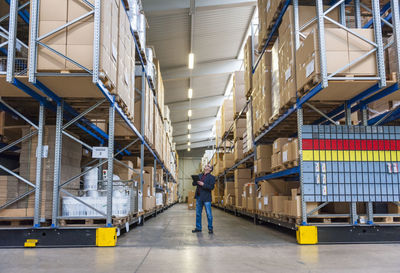 Manager checking goods in storage hall of factory