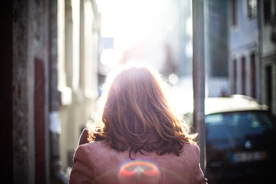 Rear view of woman standing against window in city