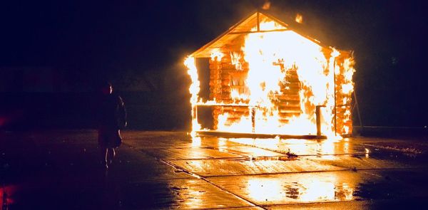 People standing by illuminated fire at night