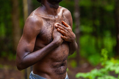 Midsection of shirtless man standing against blurred background