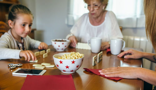 Close-up of family playing dominoes while having food at table