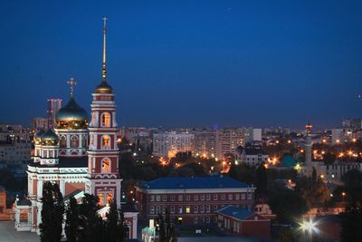 Illuminated city against clear blue sky at night