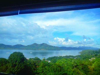 Scenic view of lake and mountains against cloudy sky