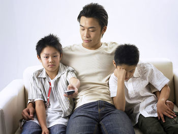 Father sitting with sons against wall on sofa