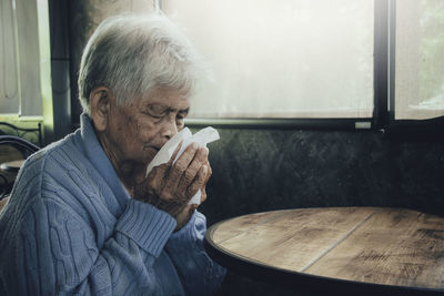 Midsection of man holding food while sitting in kitchen