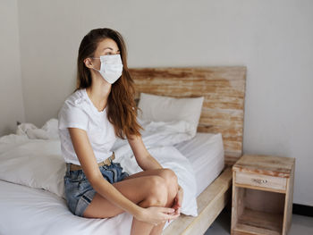 Woman sitting on bed at home