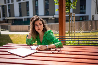 Portrait of young woman sitting on table