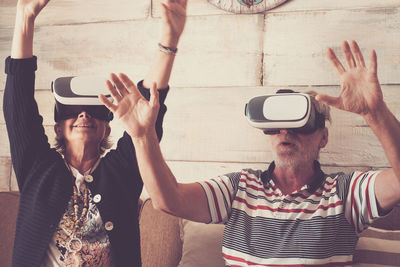 Senior couple wearing virtual reality headset at home