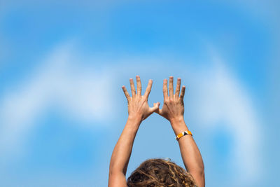 Woman with arms raised against blue sky