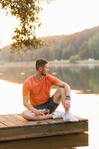 Side view of man sitting on retaining wall