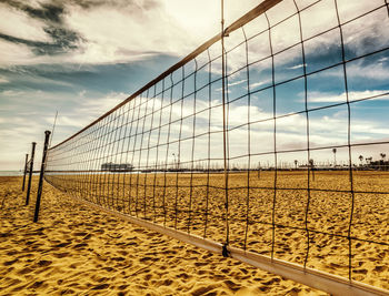 Railing on beach against sky during sunset