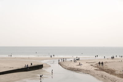 Group of people on beach against clear sky