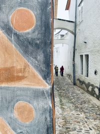 Rear view of man walking on street amidst buildings