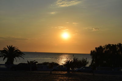 Silhouette of palm trees at beach during sunset