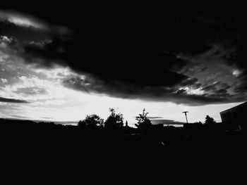 Silhouette trees and buildings against sky at sunset