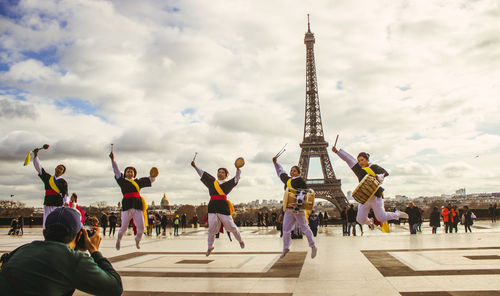 Group of people in city against cloudy sky