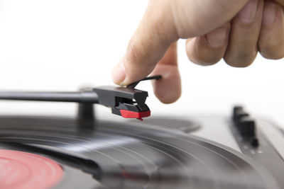 Cropped hand holding record player needle against white background