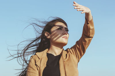 Low angle portrait of smiling young woman against sky