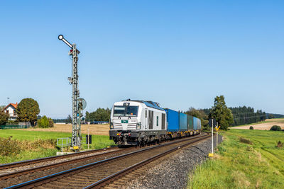 Train by railroad tracks against clear blue sky
