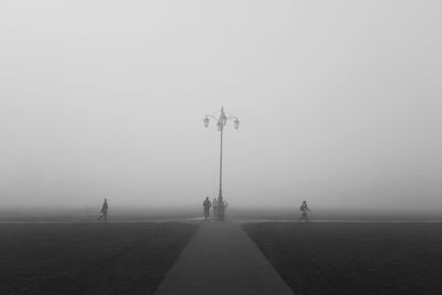 People on field against sky during foggy weather