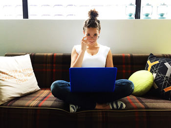 Portrait of young woman sitting on sofa
