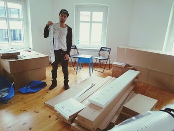 Young man standing with cardboard boxes in new houses