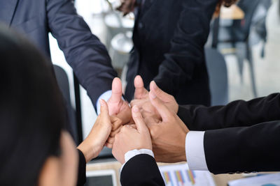 Cropped image of business people gesturing thumbs up at office