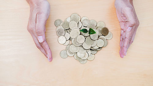 High angle view of hand holding coins on table