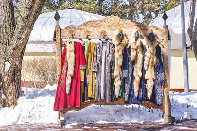 Hanger with kazakh festive colorful clothes for tourist photoshoot. traditional robes, fox fur.