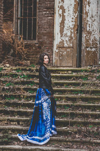 Portrait of a young woman standing against brick wall