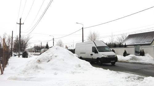 Cars on snow covered landscape against sky