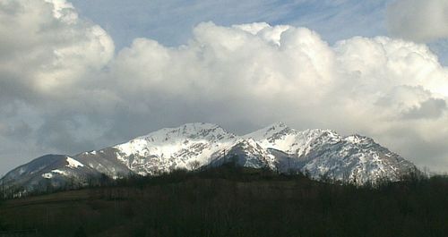 Scenic view of snow covered mountains against cloudy sky