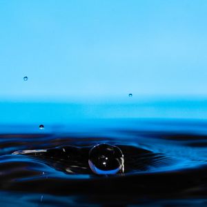 Close-up of water drop against blue sky