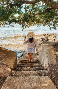 Young woman in beach clothes on stairs by sea. summer, lifestyle, vacation.