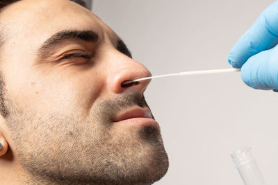 Close-up portrait of man holding hands over white background