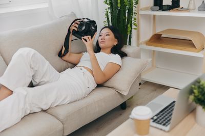 Young woman using mobile phone while lying on bed at home