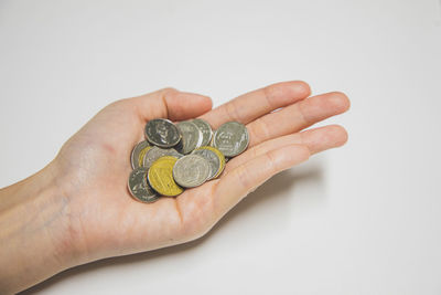 Close-up of hand holding ring over white background